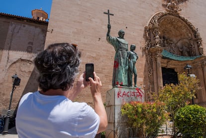 Un hombre fotografía una pintada crítica en el monumento dedicado al fraile Junípero Serra en Palma