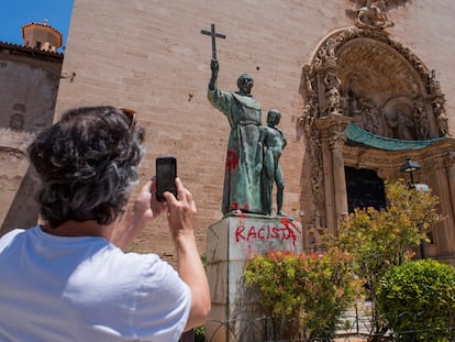 Um homem fotografa uma pichação crítica no monumento dedicado ao frade Junípero Serra em Palma de Mallorca, em 22 de junho de 2020.