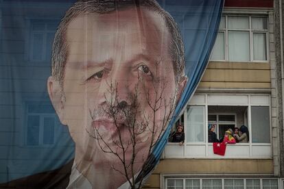 Un grupo de mujeres asomadas al balcón de un edificio, que exhibe una lona con la imagen del presidente turco Erdogan durante un mitin en Estambul con motivo del próximo referéndum constitucional.