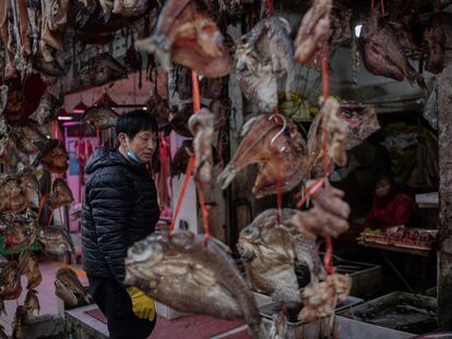 Un pescadero contempla su mercancía en un mercado de Wuhan
