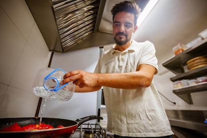 Un cocinero vierte agua de garrafa en la comida que está preparando, en un restaurante de Pozoblanco. / RAFA SÁNCHEZ