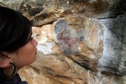 Una mujer contempla un ciervo en una de las pinturas rupestres en la zona de Prades.