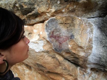 Una mujer contempla un ciervo en una de las pinturas rupestres en la zona de Prades.