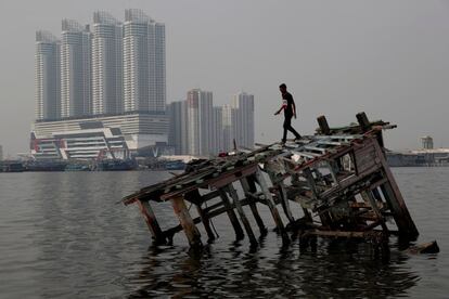 Un joven camina sobre los restos de un bote de madera al norte de Yakarta, Indonesia.