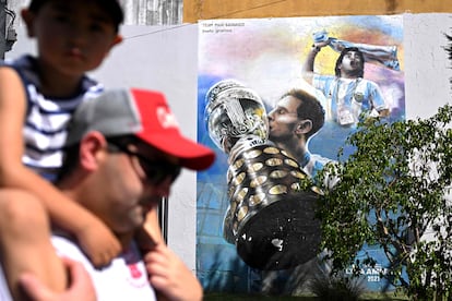 Un padre y su hijo pasan al lado de un mural con Messi y Maradona en Buenos Aires.