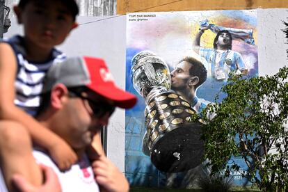 Un padre y su hijo pasan al lado de un mural con Messi y Maradona en Buenos Aires.