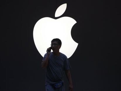 Un hombre pasa frente al logo de Apple en Shanghai