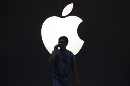 Un hombre pasa frente al logo de Apple en Shanghai