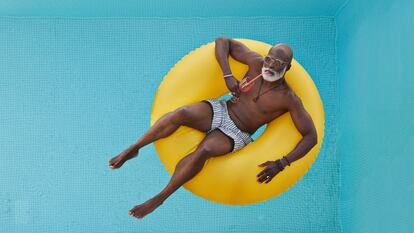 Un hombre flota en la piscina sobre un dónut hinchable.