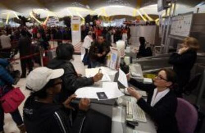 Varios pasajeros son atendidos en los mostradores de facturaci&oacute;n de Iberia en Barajas, con miles de trabajadores de fondo participando en la concentraci&oacute;n del viernes en la T4. 