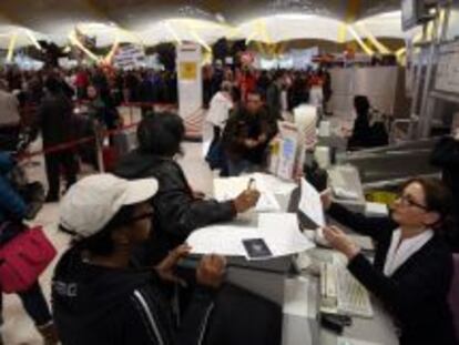 Varios pasajeros son atendidos en los mostradores de facturaci&oacute;n de Iberia en Barajas, con miles de trabajadores de fondo participando en la concentraci&oacute;n del viernes en la T4. 