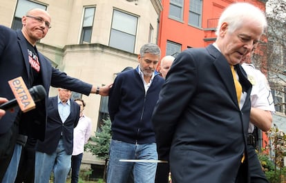 Los Clooney, esposados, son conducidos hacia un furgón policial.