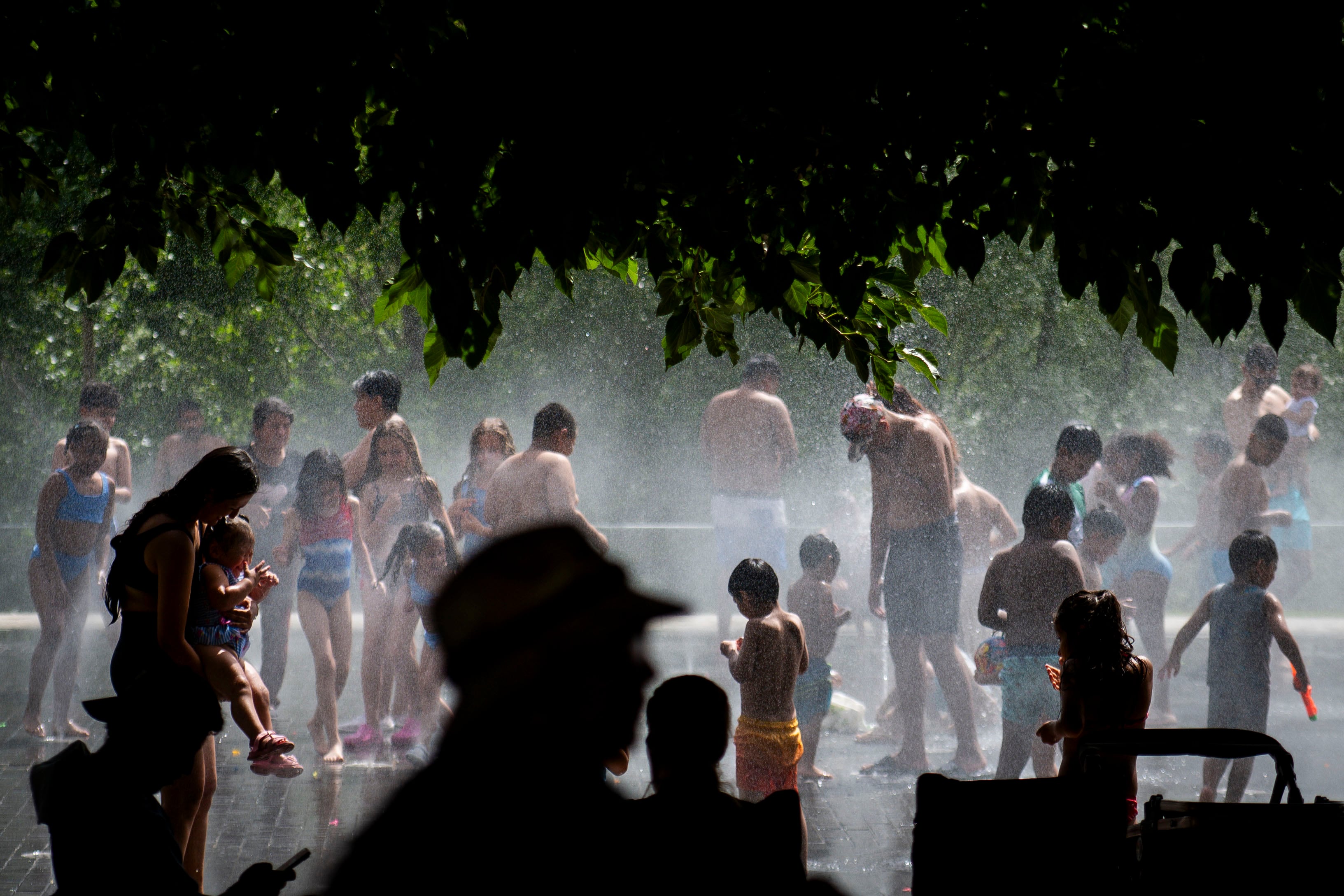 Varias personas se refrescan en las fuentes de la  playa urbana de Madrid Río.