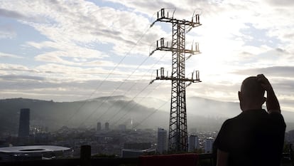 Una persona observa el cableado con el que red eléctrica transporta la energía sobre la ciudad de Bilbao.