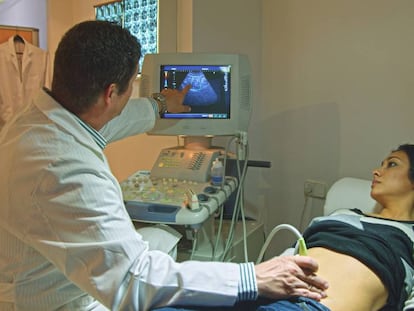 Un médico realiza una ecografía a una mujer.