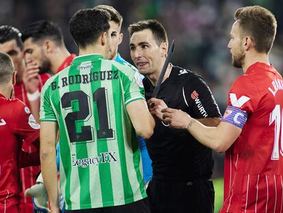 El árbitro De Burgos Bengoechea muestra el palo que impactó en Jordán al bético Guido Rodríguez.