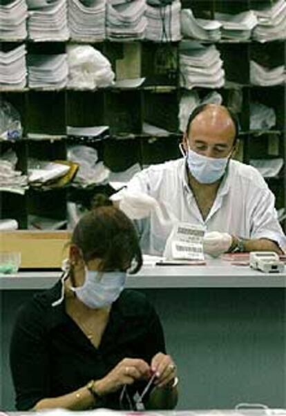 La psicosis del ántrax se ha extendido por todo el mundo. En la imagen, dos empleados de correos de Montevideo (Uruguay) se protegen con máscaras y guantes.