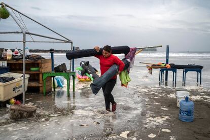 Una mujer quita sombrillas de la playa mientras las fuertes olas llegan a la costa debido al huracán 'Grace'.