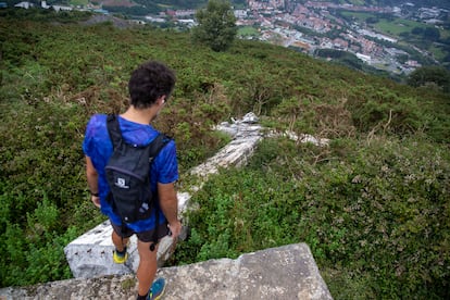 Un montañero junto a la cruz derribada en la cima del monte Buruntza, con el municipio de Andoain (Gipuzkoa) al fondo.