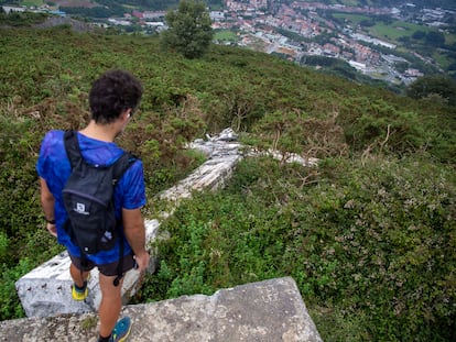 Un montañero junto a la cruz derribada en la cima del monte Buruntza, con el municipio de Andoain (Gipuzkoa) al fondo.