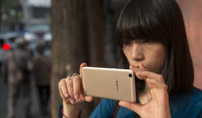 Una mujer utiliza el móvil OPPO R9.