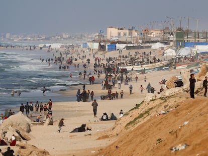 Cientos de palestinos aguardan en una playa de Gaza con la esperanza de recibir ayuda lanzada desde el aire.