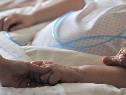 Una mujer da la mano a una anciana.