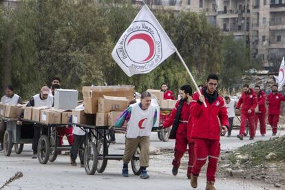 Miembros de la Media Luna Siria saca a un grupo de sirios, junto a cajas de provisiones, del barrio de Bustan al-Qasr. Este distrito, bastión rebelde en Alepo, ha sido objeto de altos el fuego entre bandos para llevar a cabo este tipo de misiones humanitarias.