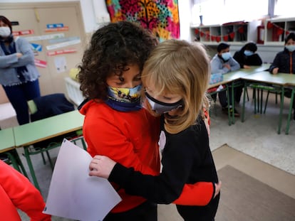 Irina, niña ucraniana recién escolarizada en España, a la derecha, recibe un dibujo hecho por una compañera en su primer día de clase.