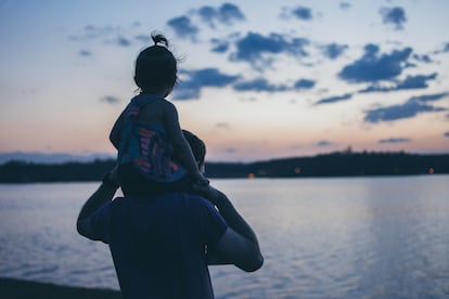 Un padre aúpa a su hijo en los hombros.