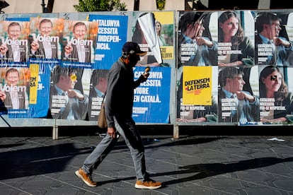 Un hombre pasa frente a carteles electorales para los comicios en Cataluña.