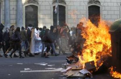 Participantes en una manifestación alternativa convocada esta tarde en Barcelona con motivo del 1 de mayo pasan ante un contenedor ardiendo. Varias personas han sido detenidas tras esta protesta por llevar a cabo actos violentos como quema de contenedores y roturas de cristales de entidades bancarias.