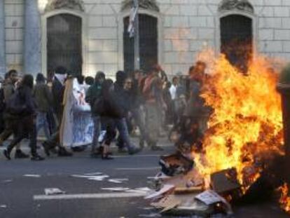 Participantes en una manifestación alternativa convocada esta tarde en Barcelona con motivo del 1 de mayo pasan ante un contenedor ardiendo. Varias personas han sido detenidas tras esta protesta por llevar a cabo actos violentos como quema de contenedores y roturas de cristales de entidades bancarias.