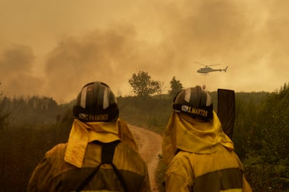 Labores de extinción del fuego en la carretera de acceso a la población de Cualedro, en Ourense, este viernes.