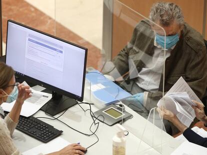 Una funcionaria atiende a dos personas en una oficina de la Agencia Tributaria en Madrid.