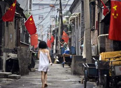 Dos niños juegan en una calle de un barrio humilde de Pekín decorada con banderas chinas con motivo de los Juegos.