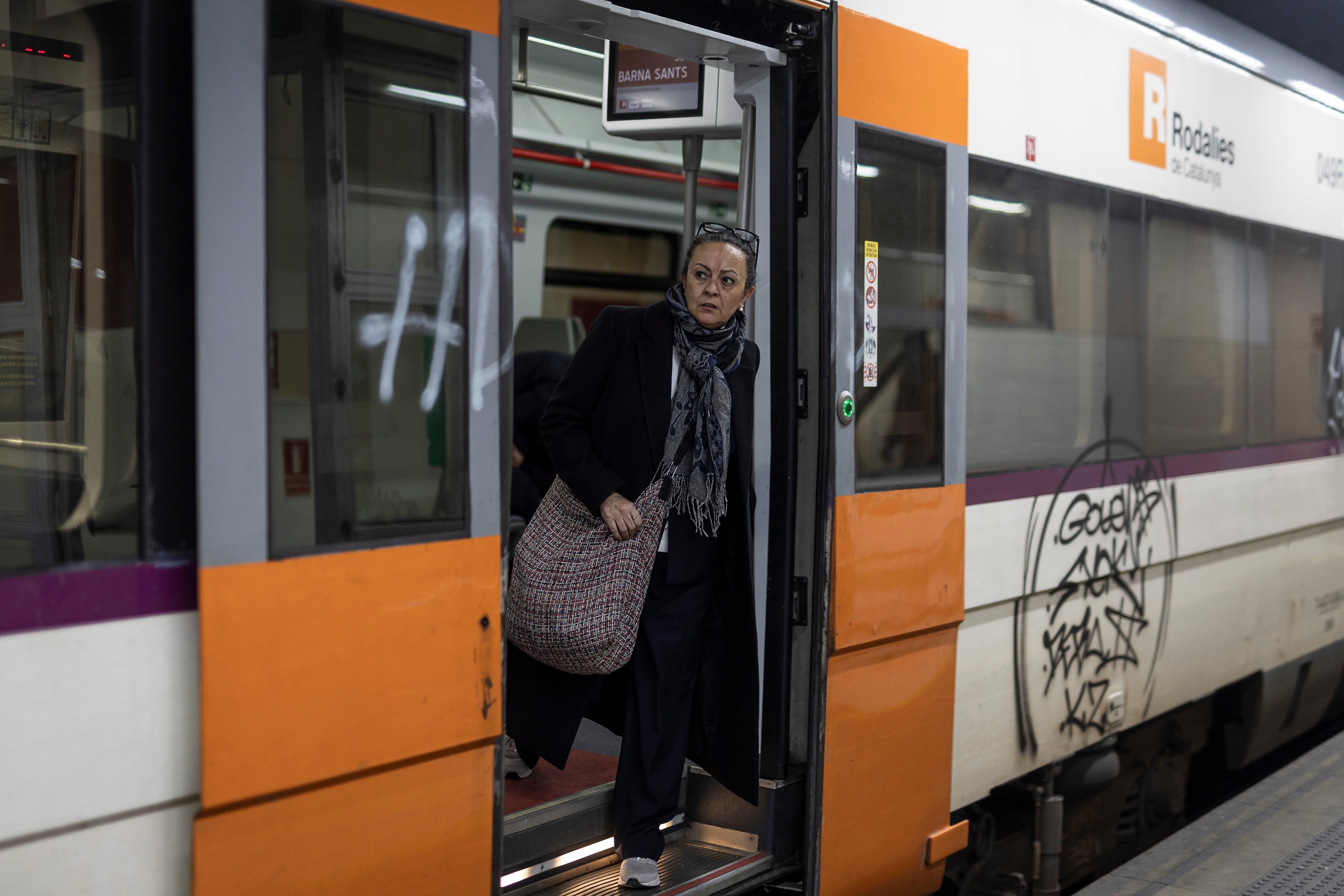 En la imagen, una mujer saca la cabeza por la puerta de un tren de Rodalies en la Estación de Sants. ALBERT GARCIA