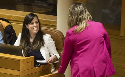 Quinteiro, de blanco, habla con la líder gallega de Podemos, Carmen Santos, desde su escaño.