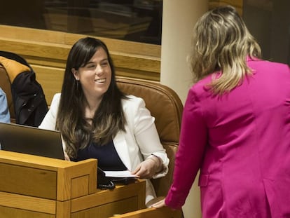 Quinteiro, de blanco, habla con la líder gallega de Podemos, Carmen Santos, desde su escaño.