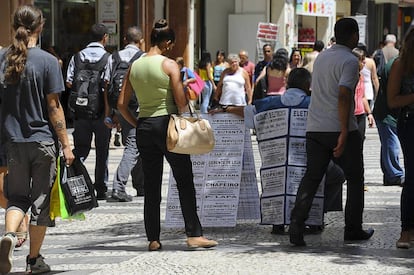 A black woman looks at job advertisements in a São Paulo street.