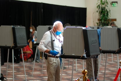 Un trabajador electoral desinfecta las mesas de votación como precaución contra el coronavirus.