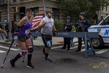 Dos corredores pasan junto a una patrulla de policía en la 4th Avenida en Brooklyn durante el Maratón de Nueva York, el 5 de noviembre de 2017.