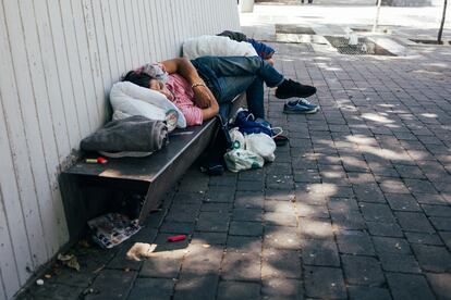 Un hombre duerme en un banco de la plaza de Tirso de Molina a media mañana. 