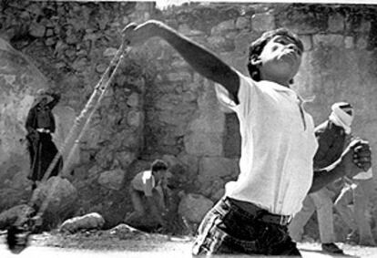 En 1987 los palestinos emprenden su Intifada (levantamiento) contra la ocupación israelí en un intento por emular la historia bíblica de David contra Goliat. En la imagen, un niño palestino lanza una piedra con su honda contra los soldados israelíes, que responden con fuego real. La foto, de julio de 1988, está tomada en Cisjordania. (REUTERS)