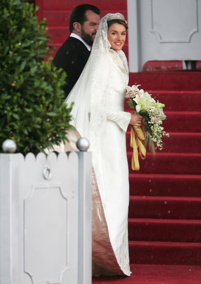 Momentos antes del inicio de la ceremonia, doña Letizia se detuvo en las escaleras de la catedral de la Almudena con el espectacular vestido de novia, obra de Manuel Pertegaz (1918-2014). Cuello en uve de resaltos volados o ‘corola’, en hilo de plata y oro platinado. Bordado con motivos como la flor de lis (versionada en vegetal y heráldica), espigas de trigo y madroños y tréboles. Las mangas, largas, estrechas y terminadas en sobre puños o manoplas con quilla y con los mismos bordados. Por delante, un triángulo subía desde el ruedo con los motivos dispuestos en rampante y en la cola, lo mismo pero abriéndose proporcionalmente. El corte se prolongaba desde los hombros, facilitando el entalle hasta llegar a la cintura, desarrollándose radialmente hasta la envergadura de la cola: 4,5 metros a partir de la cadera, con un perímetro de 16 metros. 