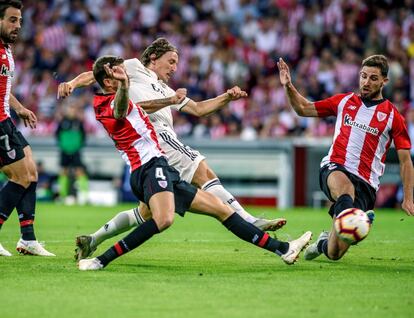 El centrocampista del Real Madrid, Luka Modric pelea contra los jugadores del Athletic de Bilbao Iñigo Martínez y Yeray Álvarez.