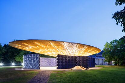 El arquitecto burkinés Francis Kéré ha sido elegido este año para realizar el pabellón de la Serpentine Gallery en Kensington Gardens (Londres), que permanecerá abierto al público hasta el 8 de octubre: un gran dosel circular de listones de madera y acero que imita la copa de un árbol. “En Burkina Faso, el árbol es un lugar donde la gente se reúne, donde las actividades del diario vivir se realizan bajo la sombra de sus ramas”, explica Kéré. Las paredes, formadas por módulos triangulares de madera de color índigo, reproducen las viviendas tradicionales africanas, con umbrales que conducen a un patio central abierto. En caso de lluvia, el techo actúa como un embudo que canaliza el agua hacia el corazón de la estructura. un sistema de drenaje en el suelo permite reutilizarla para regar el parque. Francis Kéré (Gando, Burkina Faso, 1965) fue el primer niño de su pueblo que aprendió a escribir. Viajó a Berlín con una beca y terminó convertido en arquitecto. Su primer proyecto fue una escuela para los niños de su poblado.