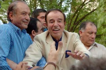 El ex presidente argentino Carlos Menem saluda a sus seguidores tras aterrizar en el aeropuerto argentino de La Rio.