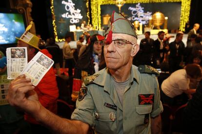 Uno de los asistentes, ataviado con indumentaria de la Legión, muestra sus décimos en el interior del Teatro Real.