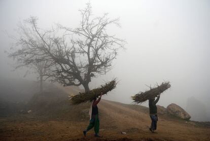 Unas mujeres llevan leña en una niebla densa en un camino a Bandipora, al norte de Srinagar, capital de Cachemira.
